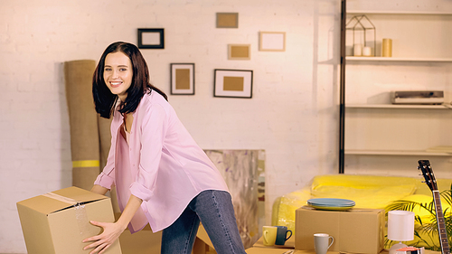 happy woman taking carton box in new home