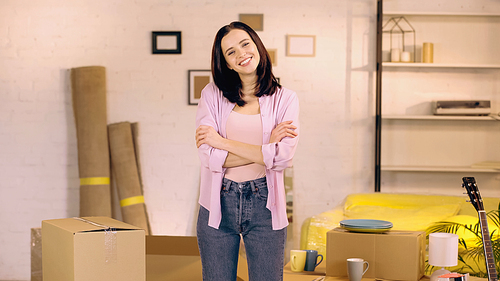 happy woman standing with crossed arms in new home