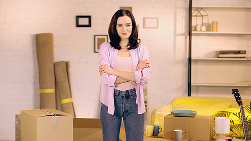 pleased woman standing with crossed arms in new home