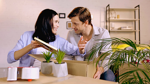 Couple talking and packing photo frame in box at home