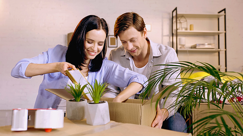 happy couple packing photo frame in box at home