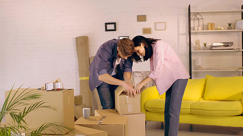 cheerful couple unpacking box in new home