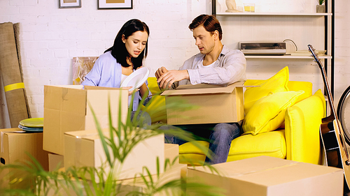 man and woman packing plates in carton boxes on couch