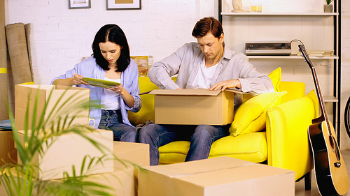 Couple unpacking plate from carton boxes on couch