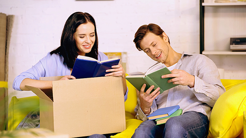 happy couple reading books on couch in new home