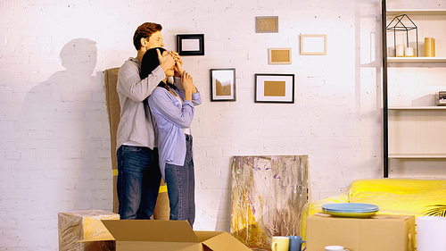 man covering eyes of girlfriend in new house