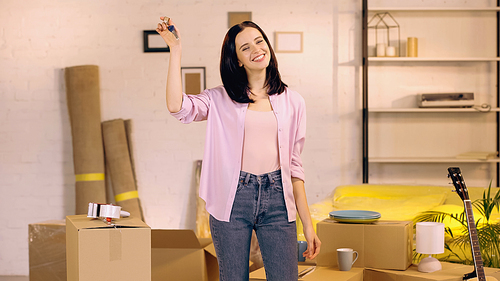 happy woman showing keys at camera in new home