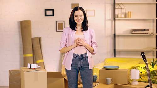 Smiling woman standing and looking at camera in new home