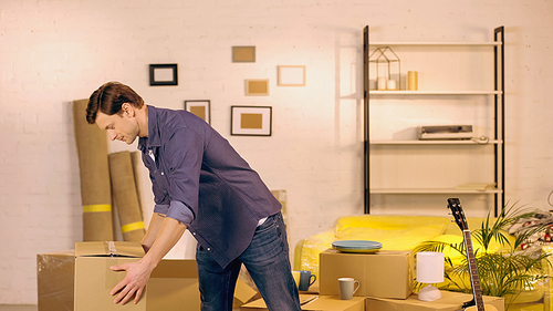 Young man putting cardboard box in new home