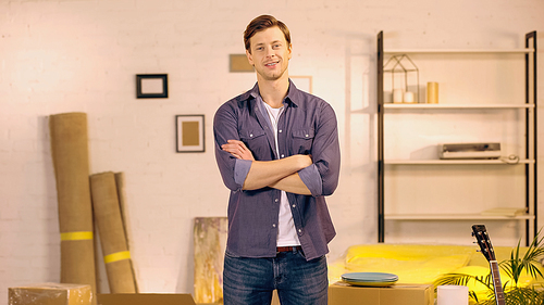 happy man standing with crossed arms in new home