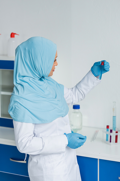 Side view of arabian scientist in hijab holding test tube