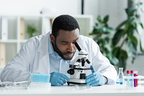 African american scientist in latex gloves working with stethoscope, test tube and flask