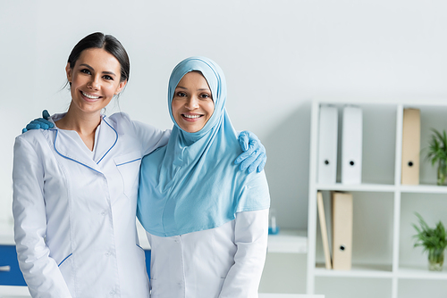 Multiethnic doctors smiling and looking at camera in clinic