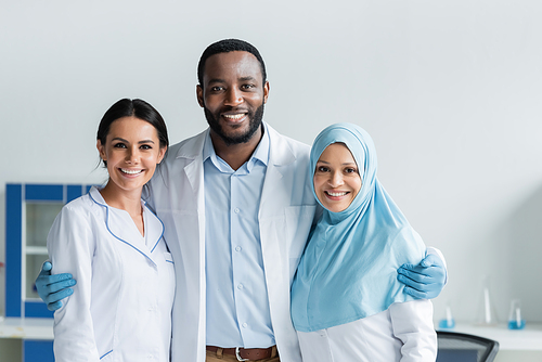 Cheerful multicultural scientists hugging in laboratory