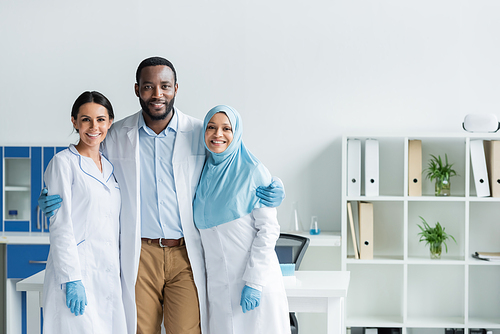 African american scientist in latex gloves hugging colleagues in lab