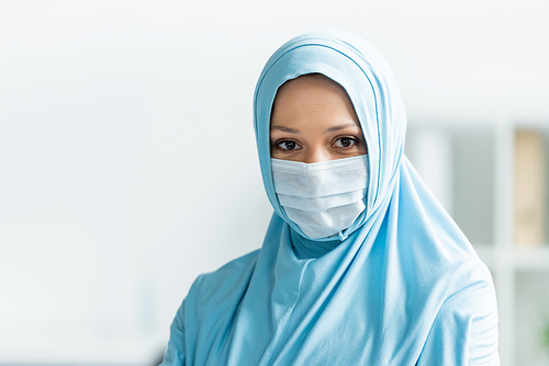 Arabian doctor in medical mask and hijab looking at camera