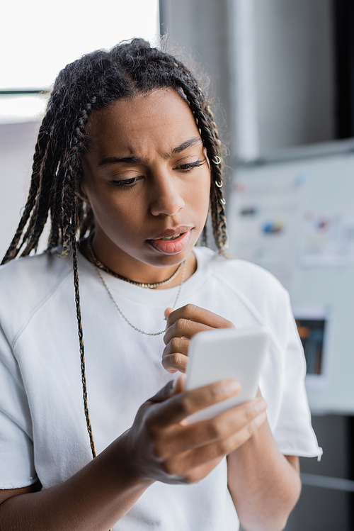 Worried african american businesswoman using cellphone in office