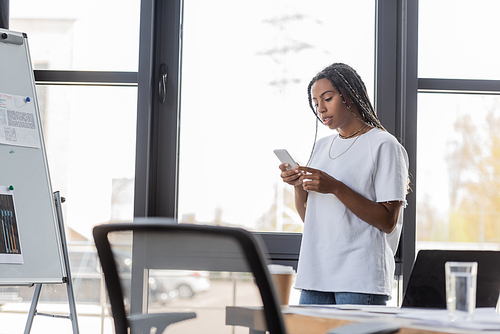 African american businesswoman in casual clothes using smartphone in office