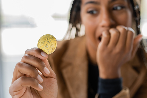 KYIV, UKRAINE - APRIL 27, 2022: Blurred african american businesswoman holding bitcoin