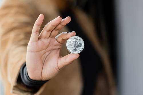 KYIV, UKRAINE - APRIL 27, 2022: Cropped view of african american businesswoman holding silver bitcoin