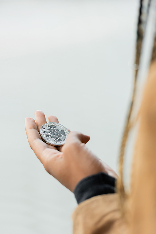 KYIV, UKRAINE - APRIL 27, 2022: Cropped view of bitcoin on hand of african american businesswoman