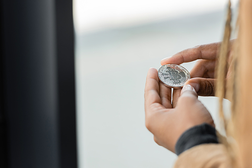 Cropped view of african american businesswoman holding silver bitcoin in office