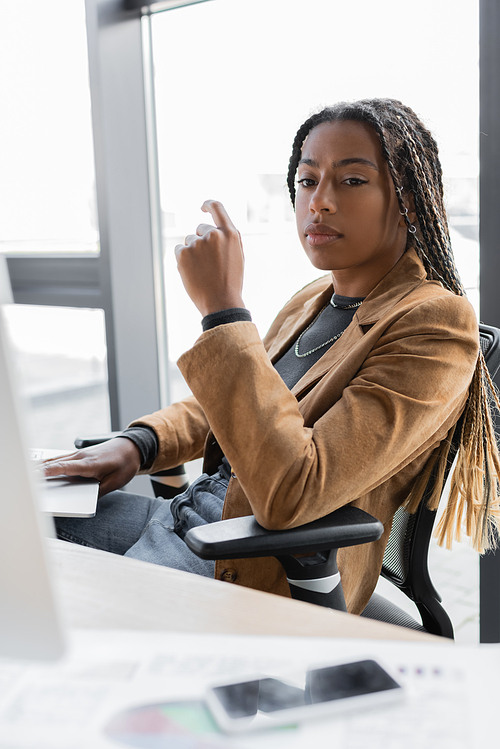 African american businesswoman using laptop and looking away in office