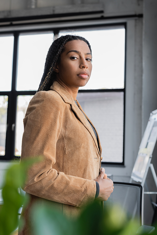 African american businesswoman in jacket looking at camera in office