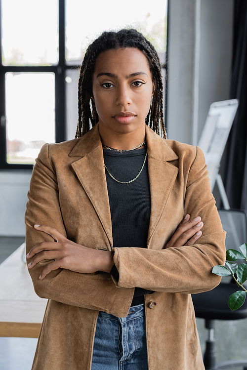 African american businesswoman in jacket crossing arms in office