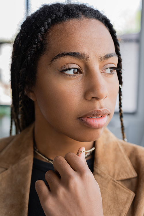 Portrait of african american businesswoman touching necklace in office