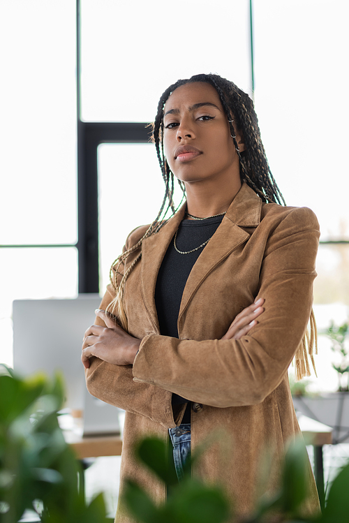 African american businesswoman in jacket crossing arms in office