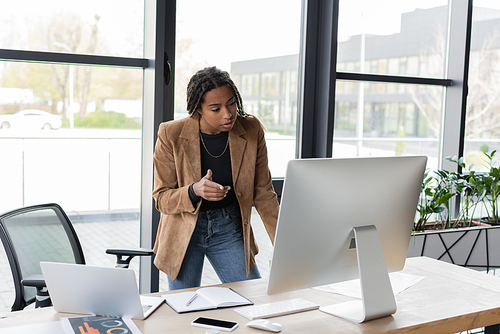 African american businesswoman pointing with finger during video call on computer on office