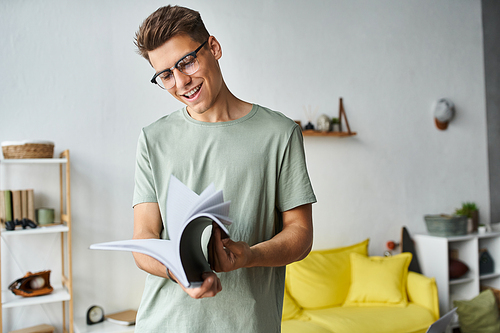 happy and charming guy with brown hair and vision glasses in living room reading notes