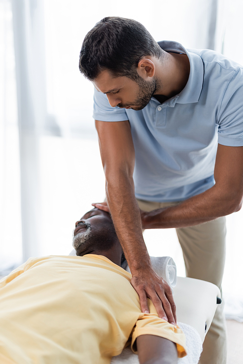 physical therapist treating mature african american man in rehab center