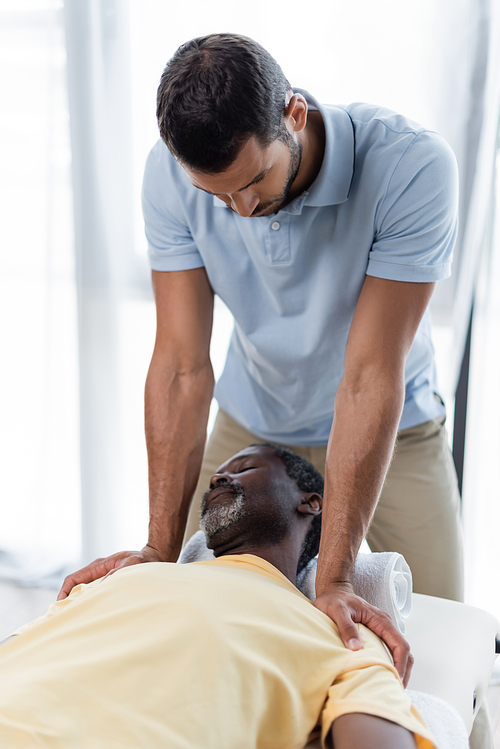 mature african american man lying on massage table during rehabilitation treatment
