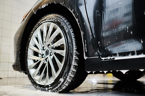 object photo of shining tired of black modern auto covered with soap during car detailing service