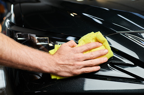 cropped view of hard working professional serviceman using small rag to clean black modern car