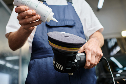 cropped view of professional dedicated worker in comfy uniform applying paste on polishing machine