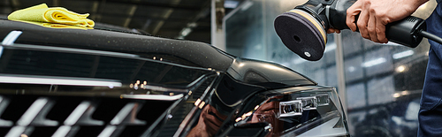 cropped view of hard working dedicated professional polishing black car with special machine