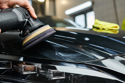 cropped view of devoted professional worker working with polishing machine carefully in garage