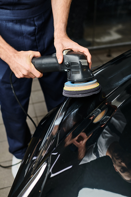 cropped view of dedicated professional worker using polishing machine carefully on black car