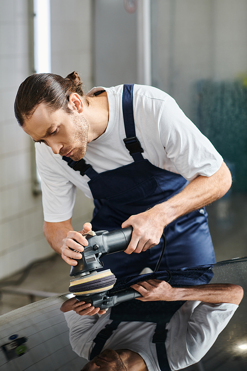 good looking dedicated worker with collected hair in uniform using polishing machine on car