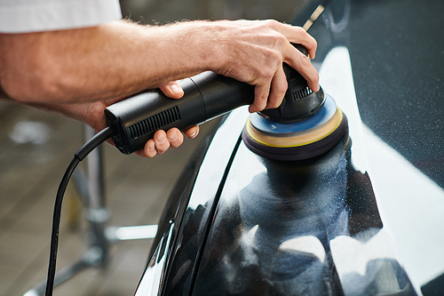 cropped view of devoted professional serviceman working carefully with polishing machine in garage