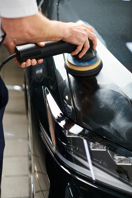 cropped view of dedicated professional serviceman using polishing machine on black modern car