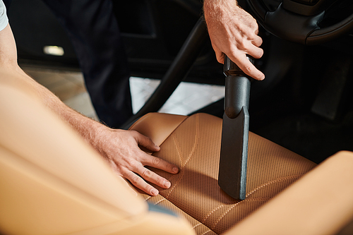 cropped view of professional dedicated worker using carefully manual vacuum cleaner in car