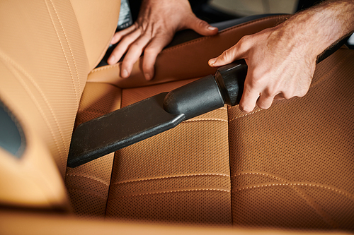 cropped view of devoted professional specialist using manual vacuum cleaner in car in garage