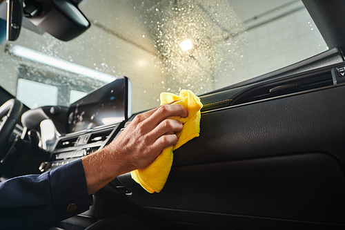 cropped view of hard working professional in uniform cleaning glove compartment with yellow rag