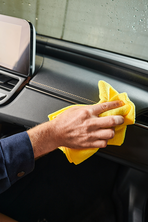 cropped view of devoted hard working serviceman in uniform cleaning glove compartment with rag