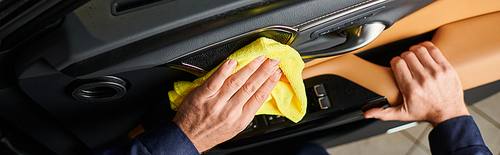 cropped view of hard working specialist in comfortable uniform cleaning car door with rag, banner