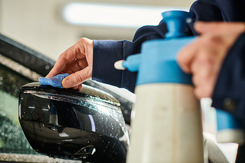 cropped view of hard working serviceman in uniform using pulverizer to clean side view mirror